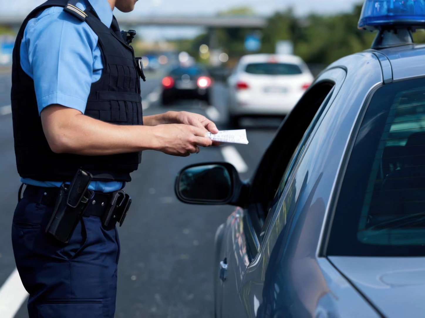 Un agente della polizia stradale consegna un verbale al conducente di un’auto